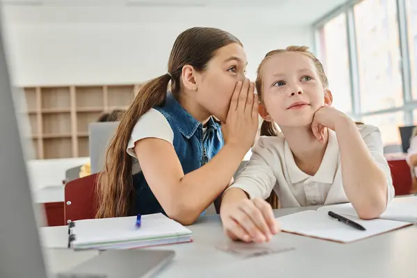 Two girls sitting at a table, gossiping lively classroom. — Stock Photo