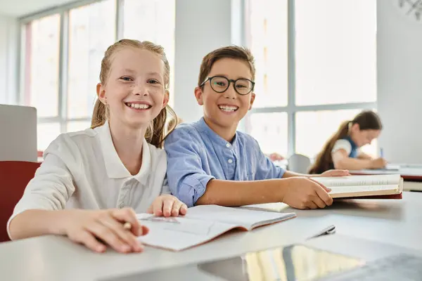 Two children, engrossed in their books, sit at a table in a vibrant classroom — Stock Photo