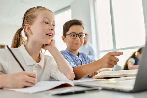 Kinder sitzen an einem Tisch in einem hellen Klassenzimmer, konzentriert auf einem Laptop-Bildschirm — Stockfoto