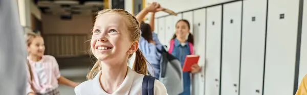 Diverse group of lively young girls standing beside lockers in a vibrant school hallway while a male teacher instructs them. — Stock Photo