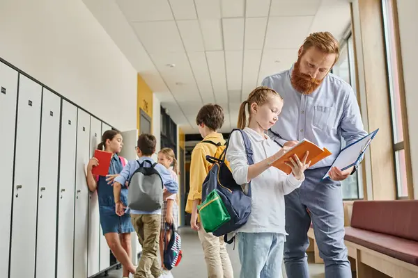 A man stands confidently next to a group of diverse kids in a hallway, engaging in mentoring or teaching activities in a bright and lively school environment. — Stock Photo