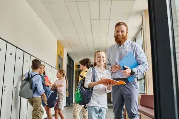 Un insegnante maschio si impegna appassionatamente con un gruppo di bambini in un corridoio vivace, condividendo conoscenze e suscitando curiosità.. — Foto stock