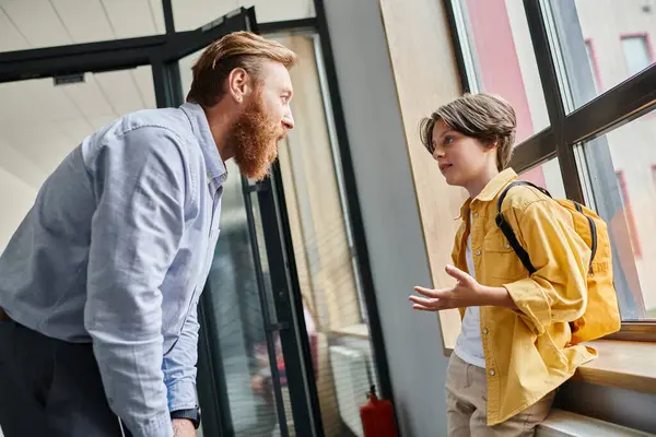 Un uomo si trova accanto a un bambino davanti a una finestra, impegnato in una conversazione riflessiva mentre guarda fuori.. — Foto stock