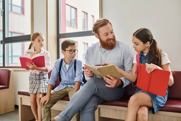 A man sits on a bench surrounded by a diverse group of children, engaging in interactive teaching and mentorship. — Stock Photo