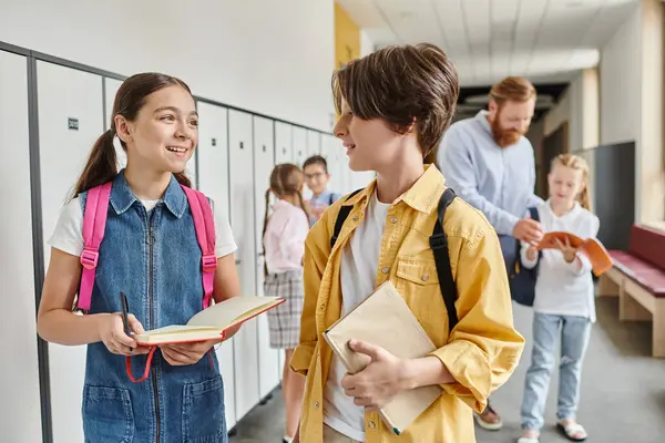 Un ragazzo e una ragazza, parte di un gruppo eterogeneo di bambini, stanno uno accanto all'altro in un corridoio, in attesa delle istruzioni del loro vivace insegnante.. — Foto stock