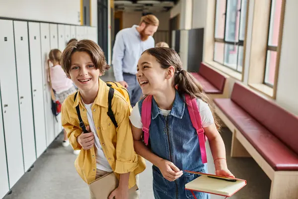 Une paire d'enfants se promenant dans un couloir bordé de casiers, trempant dans les couleurs vibrantes et l'atmosphère unique. — Photo de stock