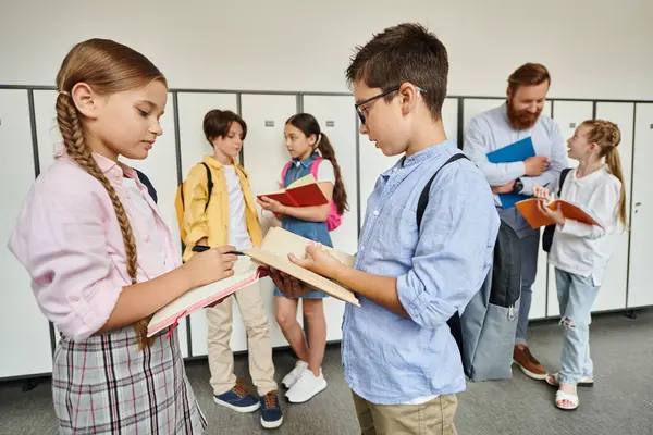 A diverse group of young kids, led by a male teacher, stand around each other in a bright and lively classroom setting. — Stock Photo