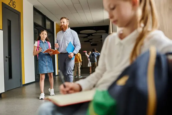 Un groupe diversifié d'enfants debout attentivement dans un couloir pendant que leur professeur donne des instructions dans un cadre de classe coloré et animé. — Photo de stock