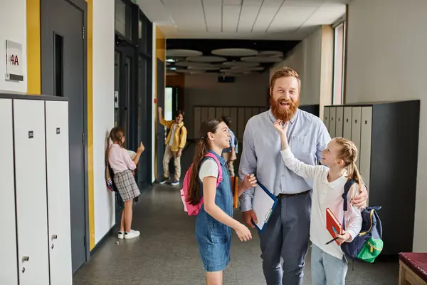 A man with a comforting presence walks down a hallway with children, guiding them with care and kindness towards their destination. — Stock Photo