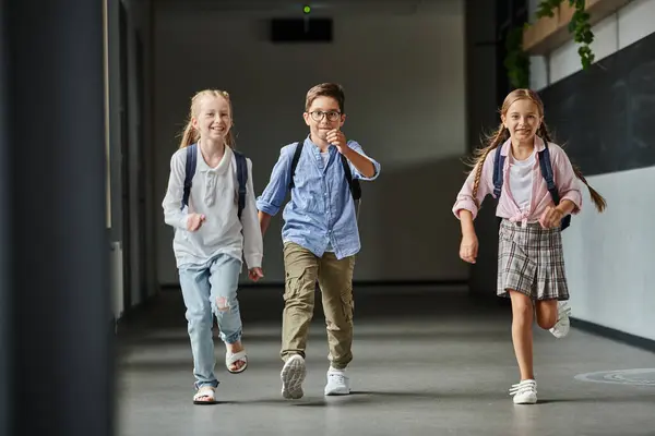 Gruppe kleiner Kinder spaziert fröhlich einen hellen Flur hinunter — Stockfoto