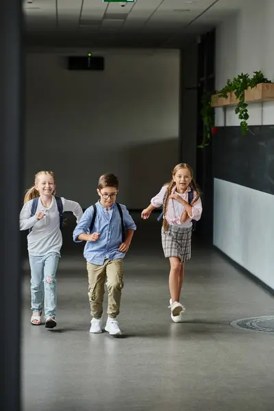 Um grupo de crianças pequenas rindo e correndo por um corredor, cheio de emoção e energia. — Fotografia de Stock