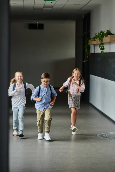 A group of young children laughing and running through a hallway, filled with excitement and energy. — Stock Photo