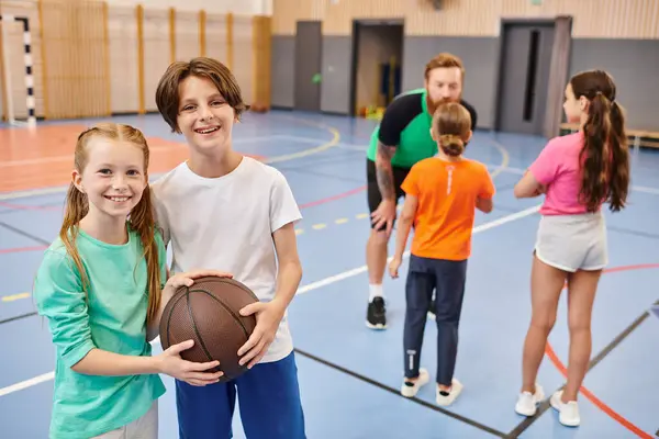 Gruppo di bambini, tra cui un insegnante di uomo, impegnati in attività di basket in un ambiente di palestra. — Foto stock