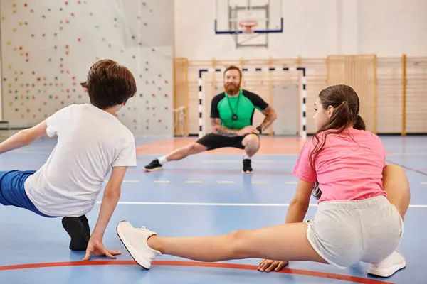 Un grupo diverso de niños participan en un entrenamiento intenso en el gimnasio de la escuela - foto de stock