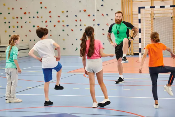 A diverse group of students stands joyfully on a gym floor while receiving guidance from their teacher in a bright classroom setting. — Stock Photo