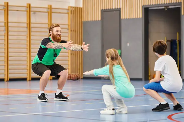 Un grupo de personas participan con entusiasmo en una clase de educación física en un gimnasio escolar - foto de stock