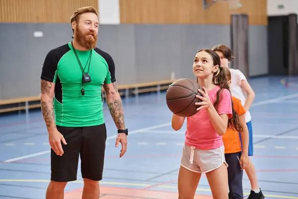 Ein Mann steht neben einem Mädchen und hält in einem dynamischen und einnehmenden Moment einen Basketball in der Hand. — Stockfoto