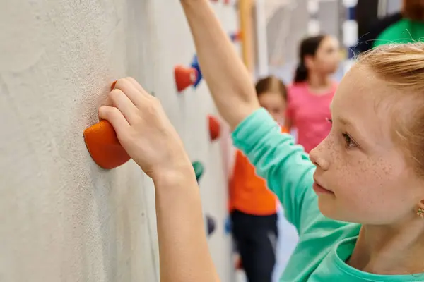 A young girl courageously climbs the side of a wall, showcasing her determination and strength in a challenging feat. — Stock Photo