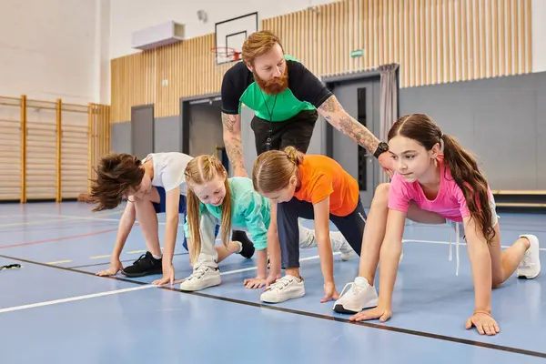 A diverse group of kids are engaging in a synchronized session of push ups on a gym floor, guided by their instructor. — Stock Photo