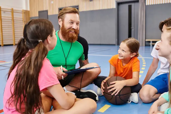 Un homme est assis sur le sol entouré d'un groupe d'enfants, enseignant avec enthousiasme dans un cadre de classe coloré. — Photo de stock