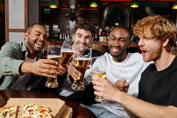 Gruppo di amici maschi interrazziali felici brindare bicchieri di birra nel bar, uomini durante l'addio al celibato — Stock Photo