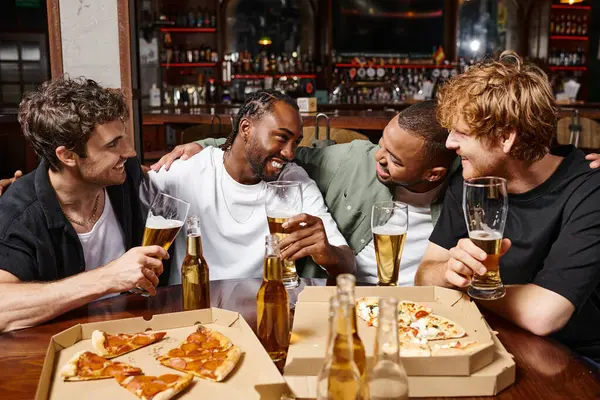 Grupo de amigos felizes multiculturais do sexo masculino conversando e segurando copos de cerveja, passar tempo no bar — Fotografia de Stock
