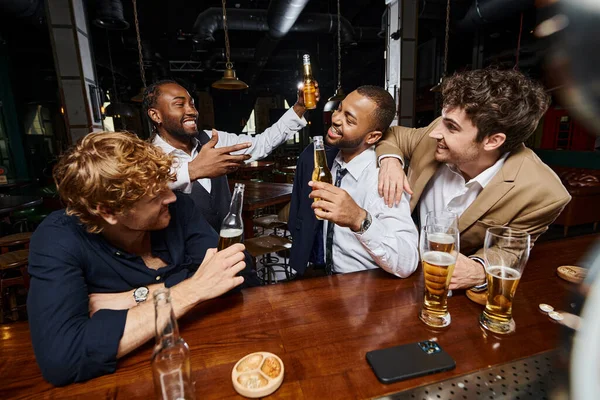 Gruppe von interrassischen glücklichen Kollegen in offizieller Kleidung trinken Bier in der Bar und haben Spaß nach der Arbeit — Stockfoto