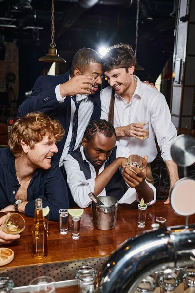 Betrunkene und lustige interrassische Freunde, die sich nach Feierabend in einer Bar umarmen, nachdem sie mehrere alkoholische Getränke getrunken haben — Stockfoto