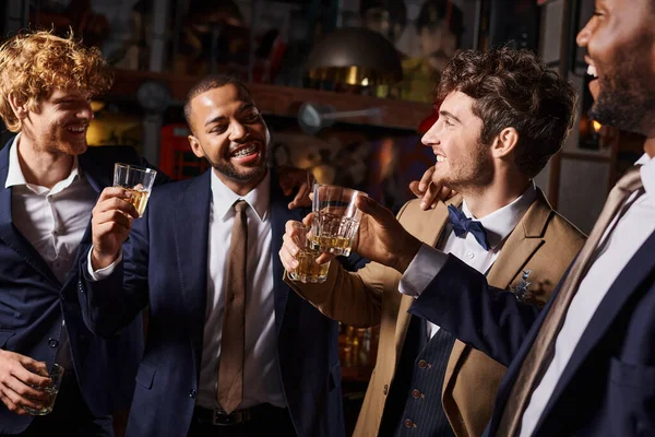 Addio al celibato, felici uomini interrazziale brindare con bicchieri di whisky nel bar, sposo e migliori uomini — Foto stock