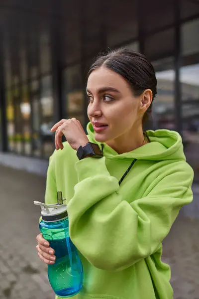 Tecnología para el deporte y la vida activa, deportista sosteniendo la botella y hablando en reloj inteligente - foto de stock