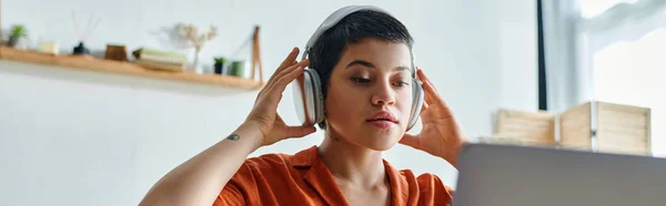 Young student with short hair with headphones and tattoo studying at her laptop, education, banner — Stock Photo