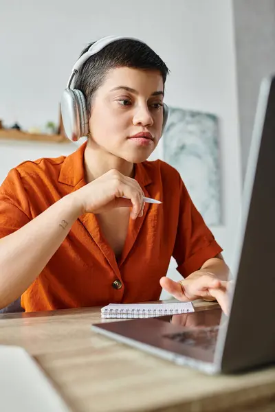 Tiro vertical de la joven estudiante enfocada con la pluma en las manos estudiando en su computadora portátil, educación - foto de stock