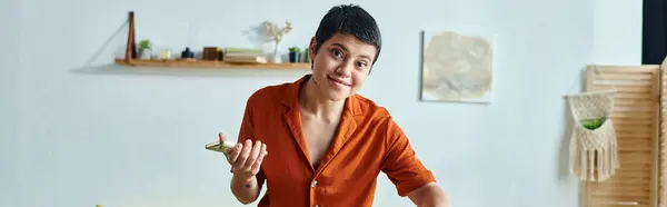 Mujer atractiva alegre en camisa naranja sosteniendo el teléfono móvil y mirando a la cámara, estudiando, pancarta - foto de stock