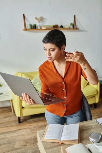 Vertical shot of pensive attractive woman gesturing and looking at camera during online lesson — Stock Photo