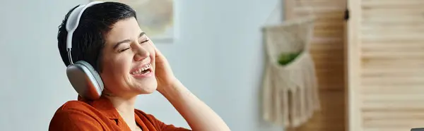 Estudiante alegre con auriculares y piercing riendo durante la clase remota, educación, pancarta - foto de stock