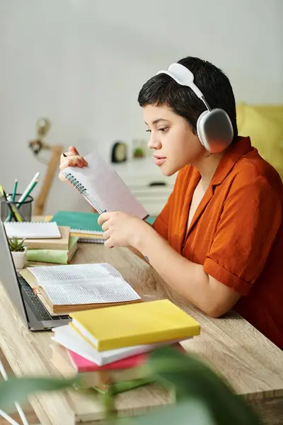 Tiro vertical de joven estudiante atractivo con auriculares que estudian duro y mirando el ordenador portátil - foto de stock