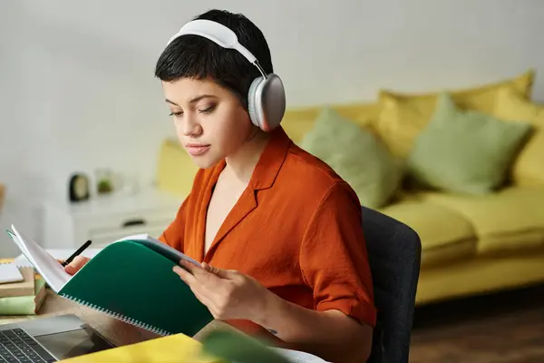 Mujer bonita pensativa en ropa de casa casual mirando el libro de texto durante la clase en línea, la educación en el hogar - foto de stock