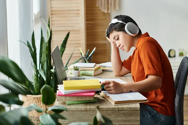 Mujer atractiva y relajada en camisa naranja con auriculares estudiando en sus notas en casa, educación - foto de stock