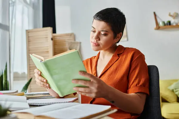 Good looking pensive female student looking at textbook and sitting at desk, education at home — Stock Photo