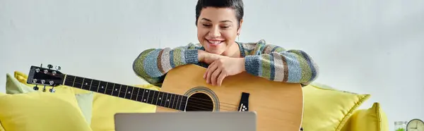 Mujer alegre sonriendo a la cámara del ordenador portátil durante la lección de guitarra en línea, la educación en casa, pancarta - foto de stock