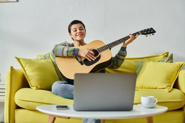 Joyous attractive woman in casual homewear attending online guitar lesson, education at home — Stock Photo