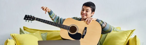 Joven alegre mujer en traje casual aprender a tocar la guitarra en clase remota, educación, bandera - foto de stock