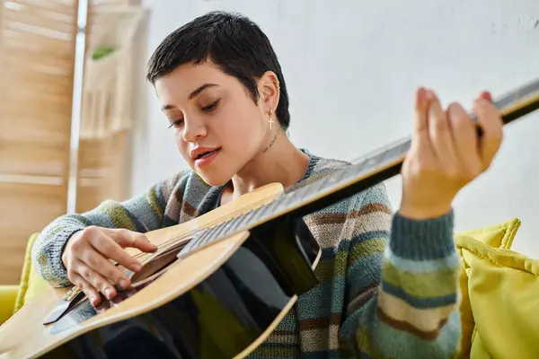Jeune femme concentrée en tenue décontractée jouant de la guitare sur une leçon de musique à distance, éducation à la maison — Photo de stock