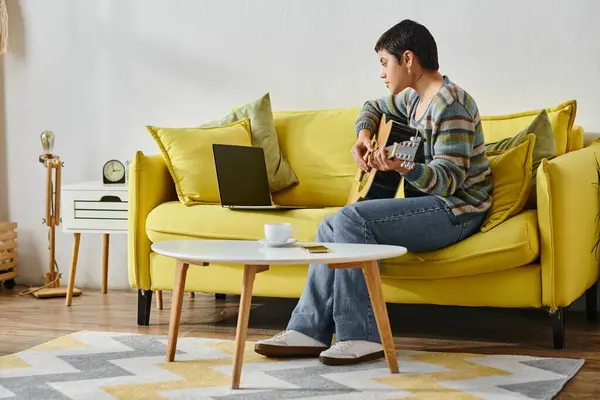 Good looking young woman in casual attire sitting on sofa attending online guitar lesson, education — Stock Photo