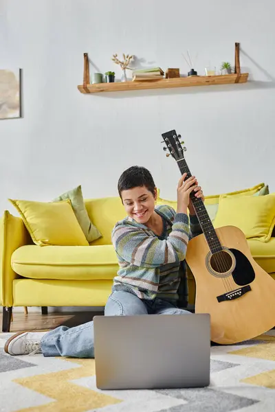 Tiro vertical de mujer guapa en traje casual vívido sentado en el suelo con la guitarra, la educación - foto de stock