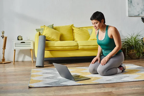 Junge sportliche Frau sitzt auf dem Boden und schaut auf Laptop vor Online-Kurs, Fitness und Sport — Stockfoto