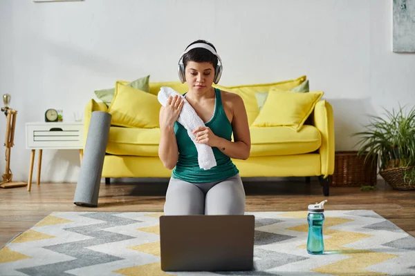 Bella donna con cuffie e asciugamano frequentare lezioni di fitness remoto, fitness e sport — Foto stock