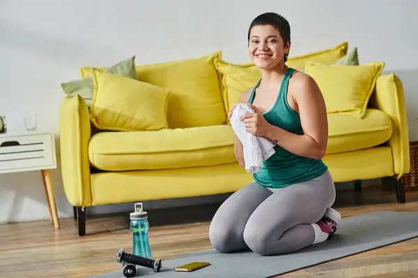 Mujer atractiva alegre sonriendo a la cámara sosteniendo la toalla después de hacer ejercicio, fitness y deporte - foto de stock
