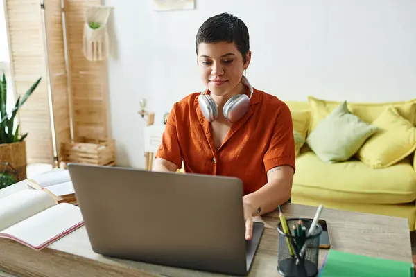Atractiva mujer joven en camisa roja con auriculares que estudian duro en el ordenador portátil, la educación en el hogar - foto de stock