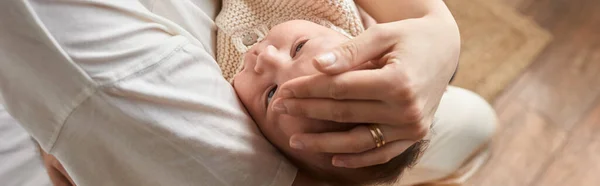 Cute newborn baby boy lying peacefully in arms of his mother, hand on head, family concept, banner — Stock Photo